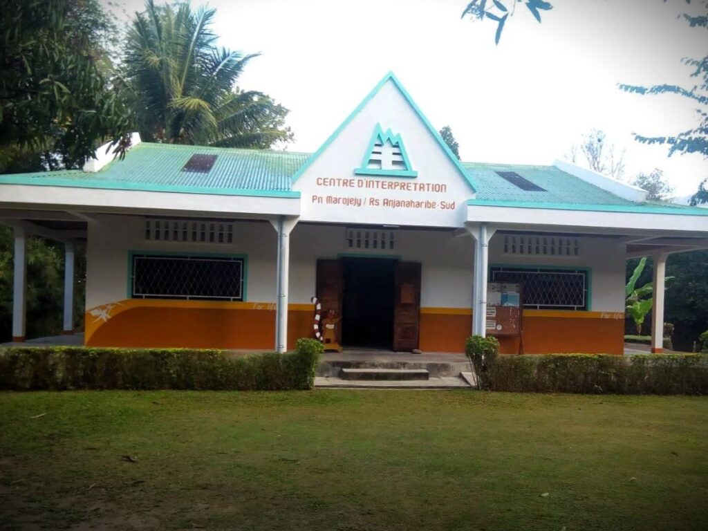 A building with a steeply-pitched roof and a sign saying "Centre d'Interpretation - PN Marojejy / RS Anjanaharibe-Sud"